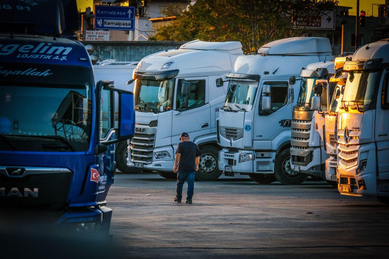 Kierowca przy rzędzie ciągników siodłowych na placu o zmierzchu